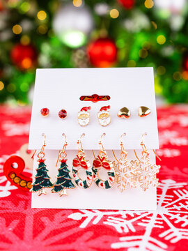 Close-up of a set of Christmas earrings featuring snowflakes, Christmas trees, Santa Claus, and other festive designs
