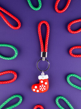 Close-up of a Christmas stocking keychain on a vibrant purple background. Festive holiday accessory with seasonal details, perfect for keys, bags, Christmas gifts, winter decorations and celebrations.