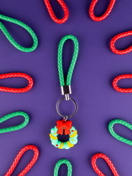 Close-up of a Christmas wreath keychain on a vibrant purple background. Festive holiday accessory with seasonal details, perfect for keys, bags, Christmas gifts, winter decorations and celebrations.