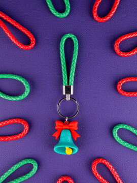Close-up of a Christmas bell keychain on a vibrant purple background. Festive holiday accessory with seasonal details, perfect for keys, bags, Christmas gifts, winter decorations and celebrations.