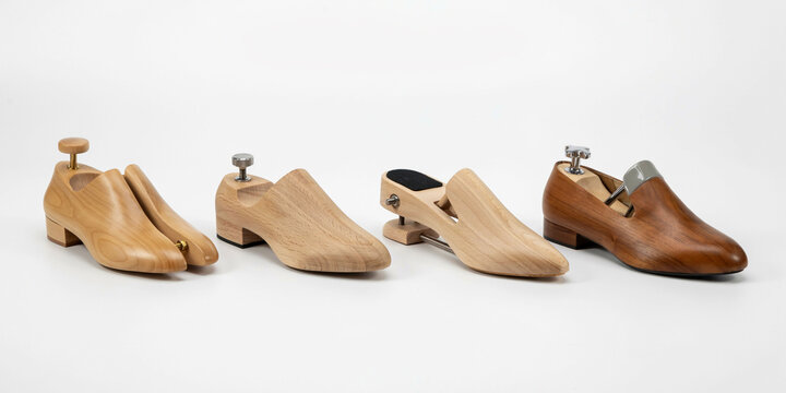 Four different wooden shoe trees for footwear maintenance on white background
