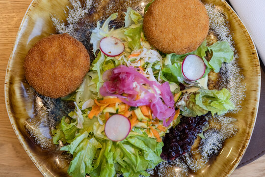 Delicious fresh side salad served with golden crispy fried croquettes and pickled red onions on ceramic plate