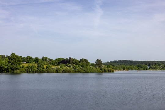 Scenic wide view of the peaceful waters surrounded by lush green forests at Lake B&uuml;tgenbach