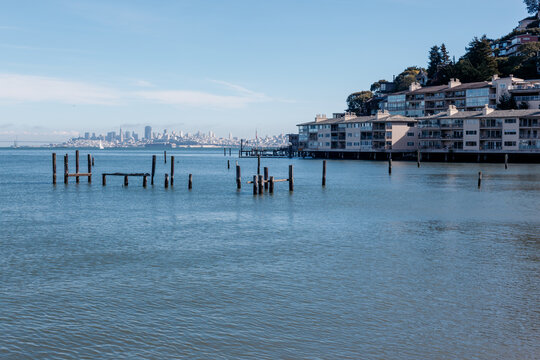 The San Francisco skyline seen across the bay from the wooden pilings of waterfront homes in Sausalito, California, USA.