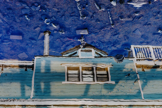 A crisp, inverted reflection of a blue house boat with a chimney in a rain puddle, captured in the harbour in  Sausalito, California, USA.