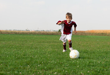 Naklejka premium Young Boy Playing Soccer on a Grassy Field