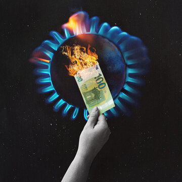  gas oven - orange tongues of blue flame of a gas burner burn the money. Hand holding 100 Euro bill as a sign of rising energy costs.