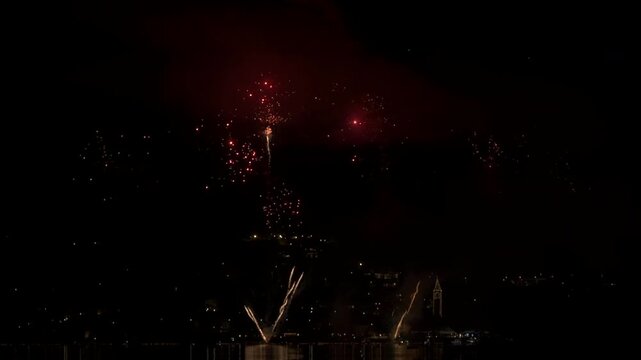 A fireworks display in the small town of Pusiano, in northern Italy. The multicolored fireworks sparkle in the sky and reflect in the water of the lake. In slow motion