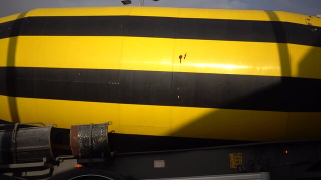 Frederikshavn, Denmark A parked yellow and black concrete truck spins in a parking lot. 