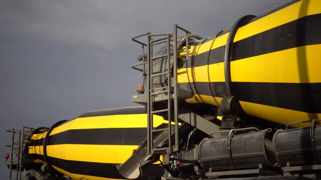 Frederikshavn, Denmark A parked yellow and black concrete truck spins in a parking lot. 