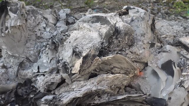 Smoldering grey ash and embers from a dying fire