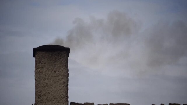Laeso, Denmark A wood burning chimney on a thatched roof with smoke used to make salt in the salt flats.  