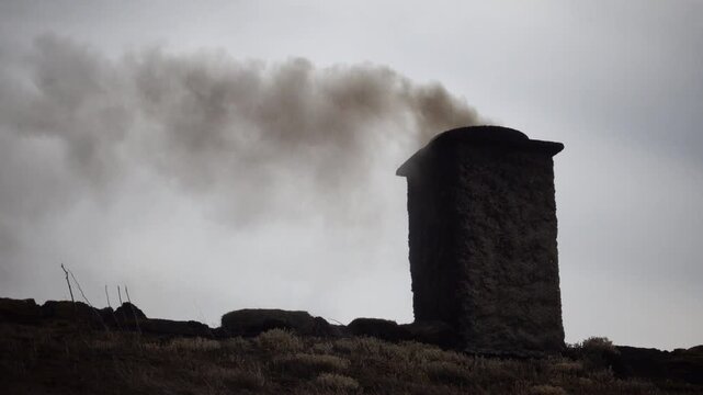 Laeso, Denmark A wood burning chimney on a thatched roof with smoke used to make salt in the salt flats.  