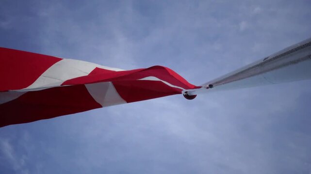 Hirtshals, Denmark A large Danish flag or Dannebrog flies in the wind on a flagpole. 