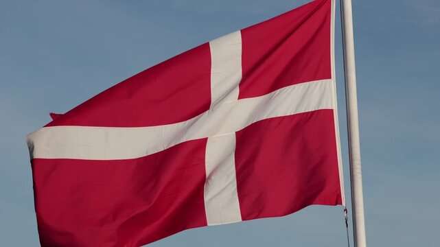 Hirtshals, Denmark A large Danish flag or Dannebrog flies in the wind on a flagpole. 