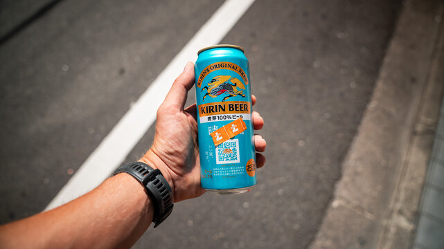 A white/caucasian male left hand holding a blue can of Kirin beer, somewhere on the streets of Kyoto