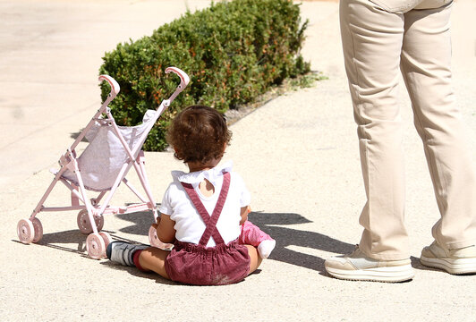 Ni&ntilde;a peque&ntilde;a con tirantes y carrito de juguete sentada en el suelo infancia, inocencia, crecimiento y juego