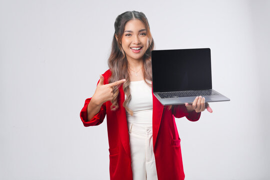 Beautiful young Asian woman wearing red jacket presenting copy space on her laptop screen.