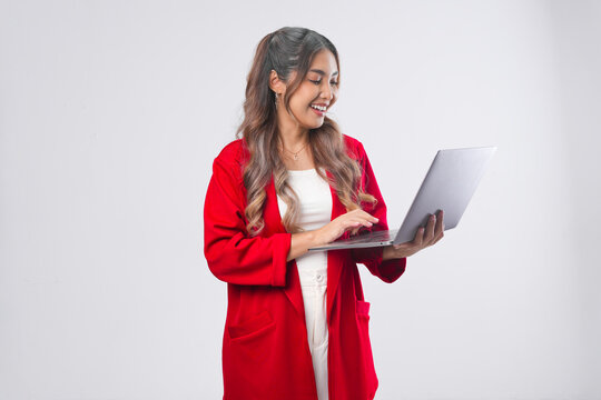Happy young Asian woman is smiling while holding a laptop and typing report.