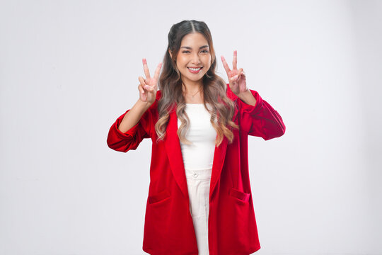 Happy young Asian woman is raising her two fingers showing peace or victory gesture.