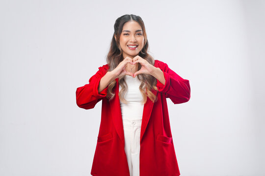 Lovely young Asian woman in a red jacket making a finger heart gestures.