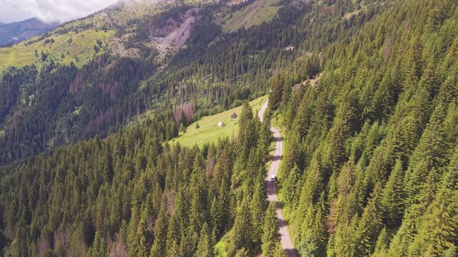 Aerial view of a white camper van driving along a serpentine mountain road past rural cabins in Kotlovi, near Montenegro Kosovo border.