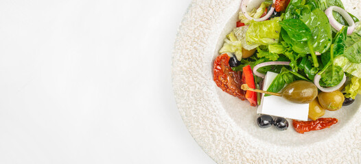 Fresh Mediterranean salad with mixed greens, olives, sun-dried tomatoes, and feta cheese served in...