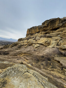 Sandstone cliff with winding formations and eroded rocky slope below.