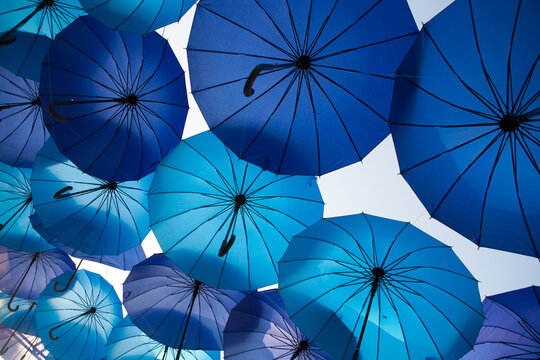 Blue umbrellas create a repeating geometric canopy in the open air, vibrant decorative installation, creative festival background.