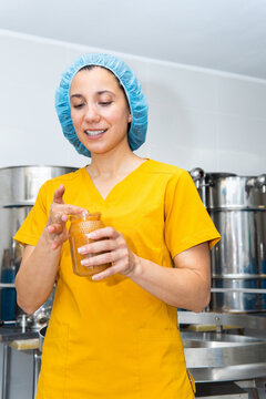 Food worker inspecting jar of natural honey production
