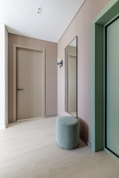 Modern Hallway Interior with Fluted Door, Pouf, and Mirror