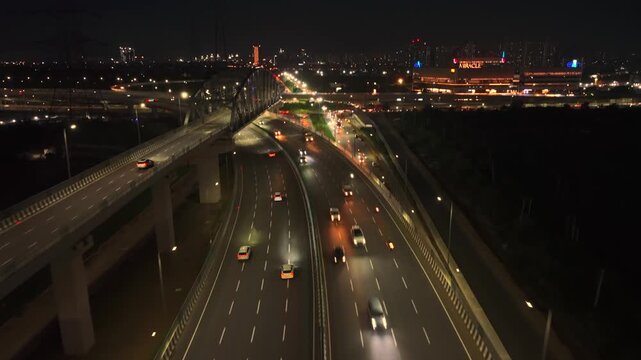 Aerial view of night traffic on a multi-lane highway with illuminated street lights and moving vehicles in Gurgaon, Haryana, India.