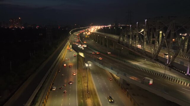 Aerial view of illuminated highway traffic and bridge structure at night in Gurgaon, Haryana, India.