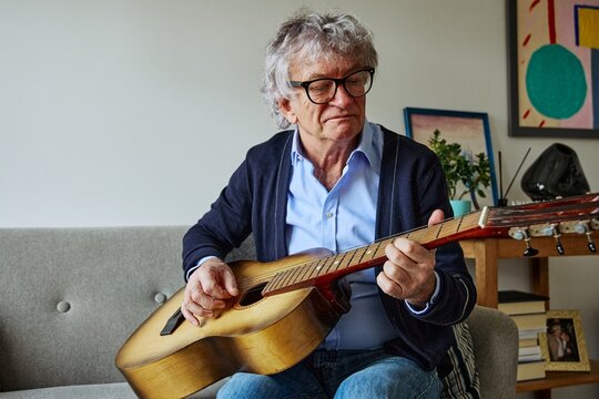 Senior man playing guitar in a bright and comfortable home interior