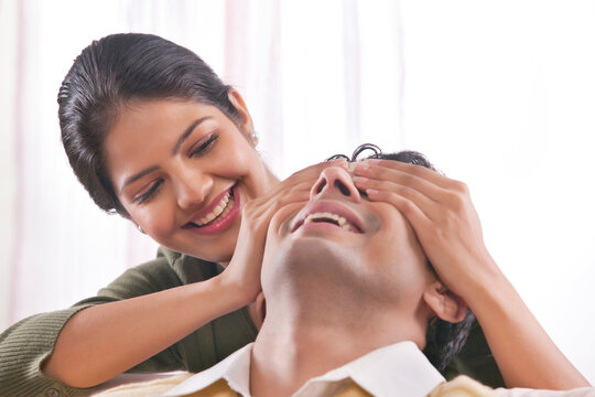 Woman covering mans eyes with her hands