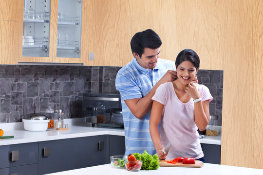 Young man fastening necklace on woman in kitchen