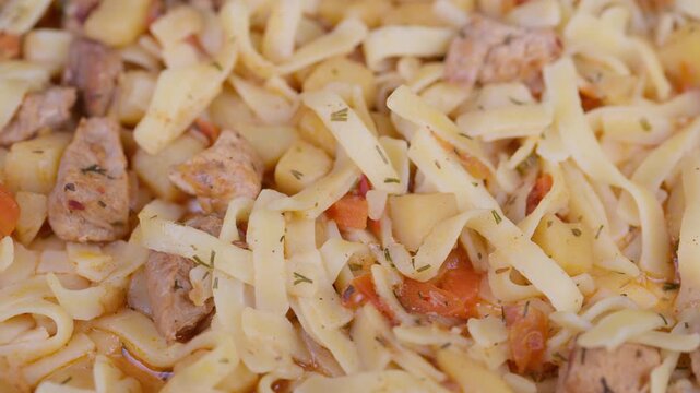 Homestyle noodle dish. Hearty braised meat and noodles. Closeup of pulled noodles with tender meat and vegetables. Rustic prepared lagman noodles featuring stewed meat and herbs