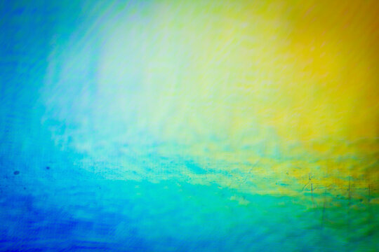 Extreme close up of abstract vibrant iridescent holographic rainbow foil background with lens flare. Glitter surface. Selective soft focus, shallow depth of field.