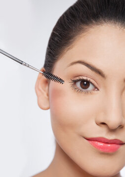 Beautiful young woman applying mascara 