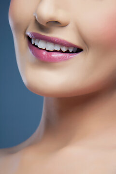 Close-up of a young woman's beautiful smile over colored background 