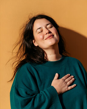 Woman with closed eyes and a palm on her chest in a moment of relief