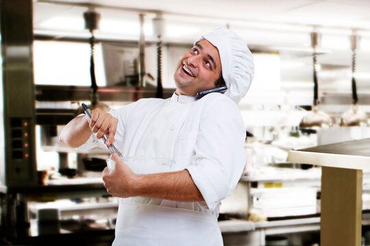 Chef talking on a mobile phone while beating dough 