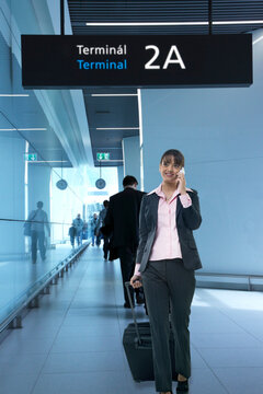 Young businesswoman with luggage using cell phone at an airport 