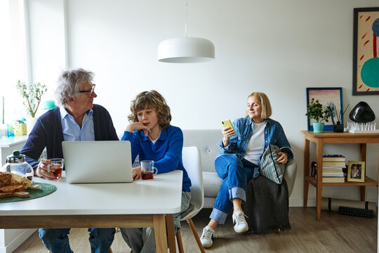 Three family members using phone in a bright and comfortable home interior