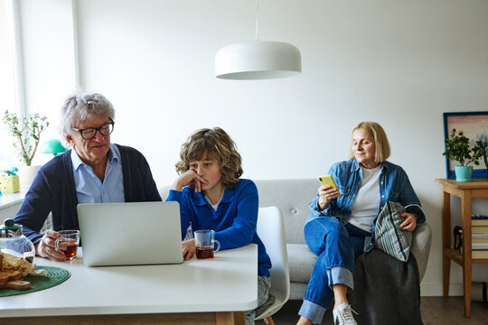 Three family members using laptop while sharing a relaxed day at home