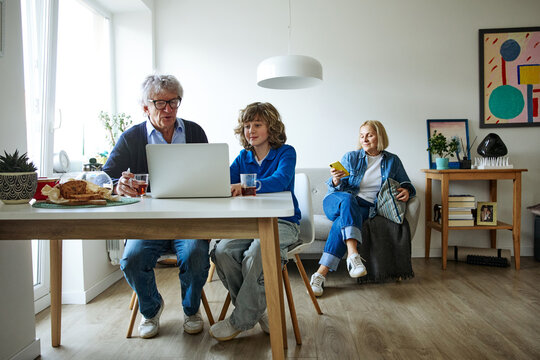 Three family members looking at laptop during an everyday family activity at home
