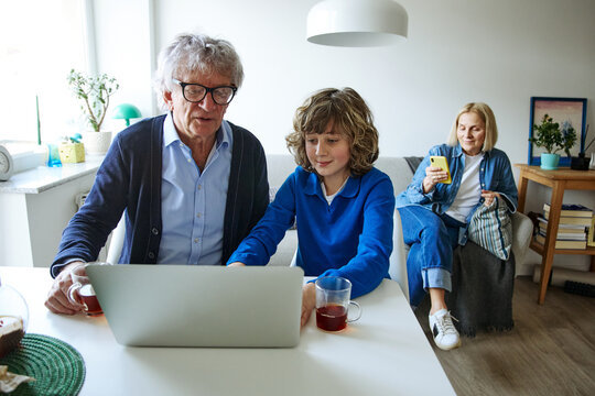 Three family members using laptop while spending time together at home