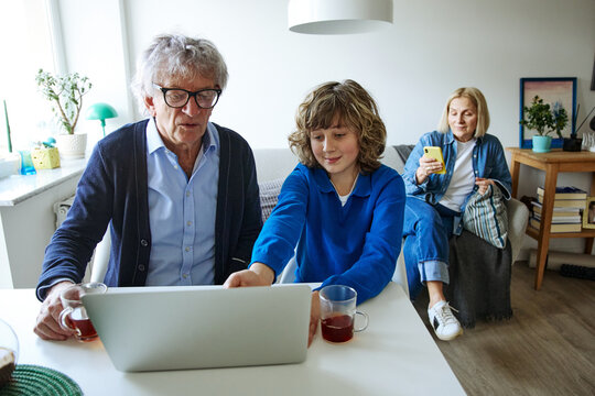 Three family members using laptop while sharing a relaxed day at home