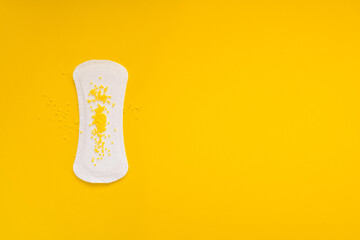  Sanitary Pad with Yellow Beads Symbolizing Urinary Leakage on Yellow Background © Mariya