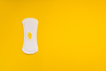 Sanitary Pad with Yellow Beads Symbolizing Urinary Leakage on Yellow Background © Mariya